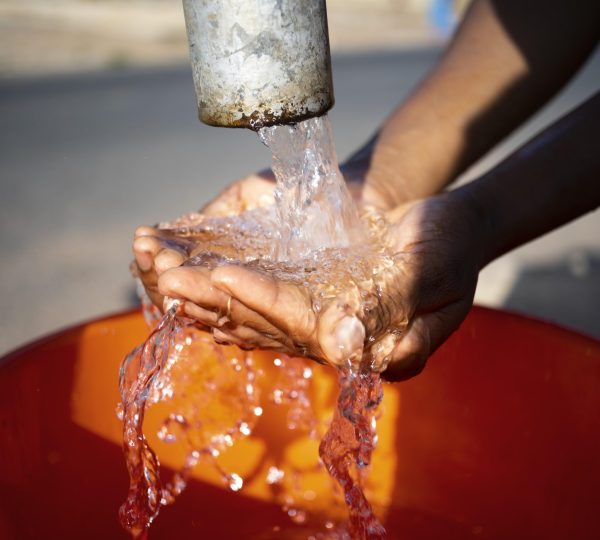 african-woman-pouring-water-recipient-outdoors